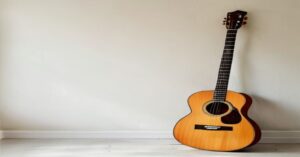 A close up view of an acoustic guitar leaning against a wall