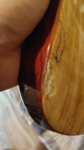 Jackson electric guitar with chipped finish and cracked clear coat after accidental drop during string change.