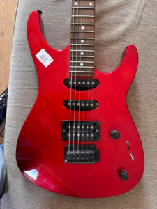 Close-up of a guitar body after the first coat of Tru-Oil showing visible streaks, uneven sheen, and light scuff-like marks before additional finish coats are applied.