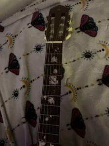 Sticker-covered Yamaha G-55 classical guitar with floral and cat decals highlighting guitar customization and self-expression.