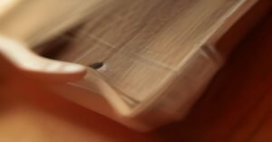 A close-up of a guitar player practicing bar chords on an acoustic guitar neck.
